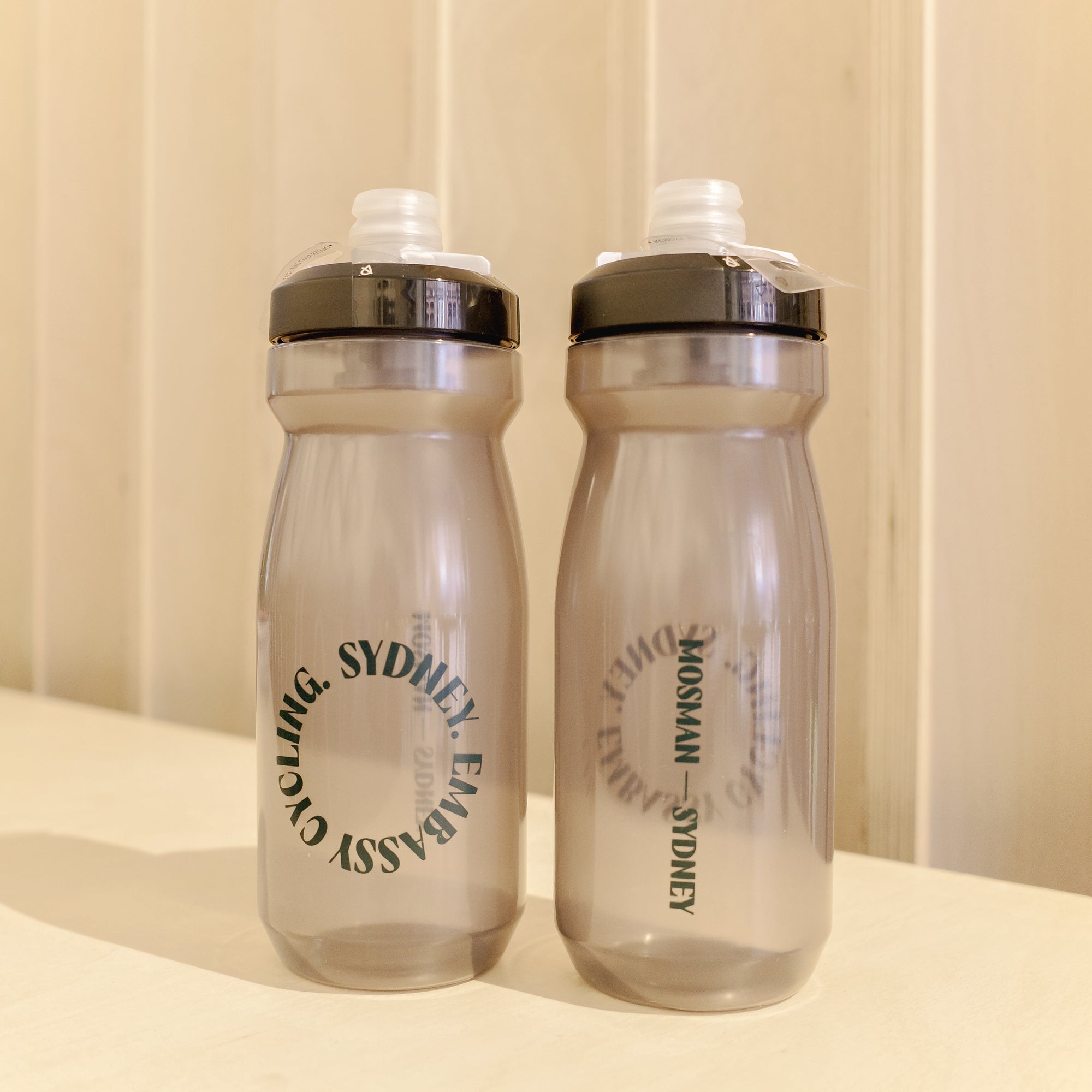 Two clear water bottles with black text on a beige background
